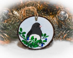A dark-eyed junco perched in leaves and berries that is hand-painted on a wood slice ornament at Cove Creek Photography.